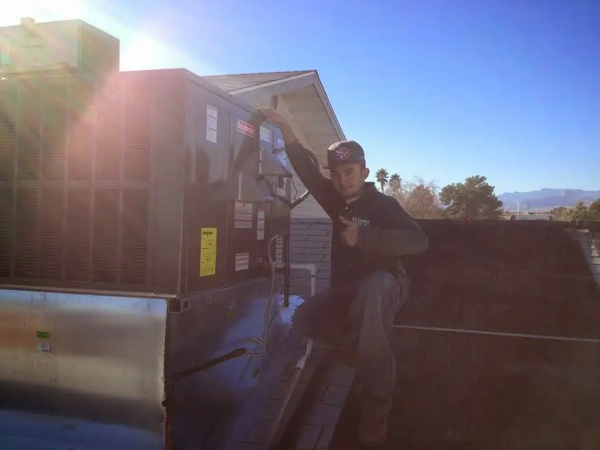 HVAC technician performing Air Duct Cleaning on a rooftop unit in Clayton